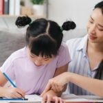Une mère aide sa fille avec les devoirs, dans le calme.