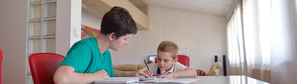 Un garçon et sa mère font les devoirs dans un environnement structuré et calme.