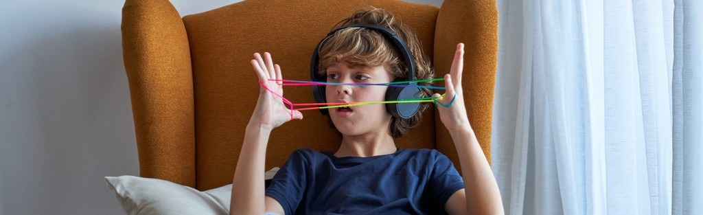 Un enfant sédentaire qui joue dans un fauteuil avec un casque sur les oreilles.