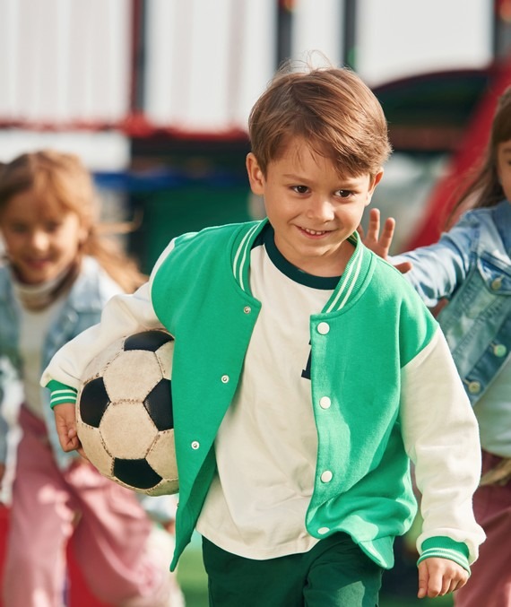 Un enfant avec un jersey porte un ballon de foot et se prépare à jouer