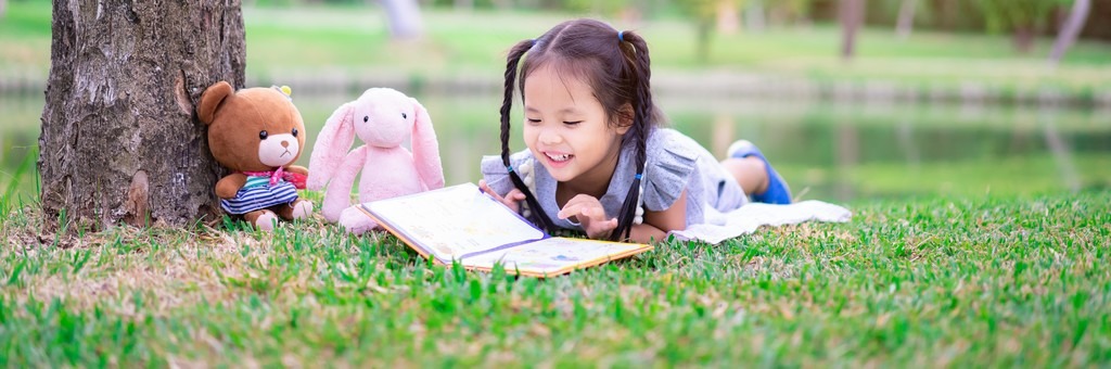 Fillette qui lit un livre avec ses peluches