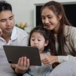 une famille (père, mère, fille) devant une tablette