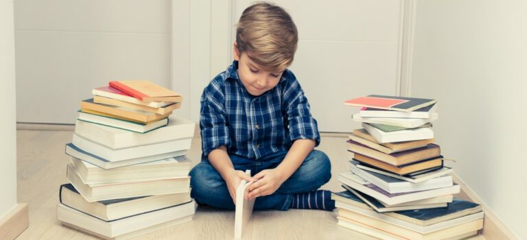 un garçon qui semble réticent à ouvrir un livre entouré de piles de livres