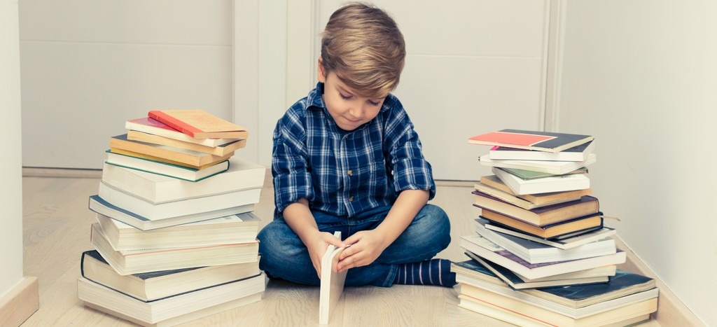 Enfant qui découvre différents livres dans un coin lecture calme.