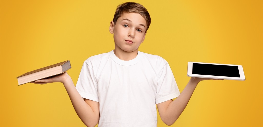 un enfant porte d'un coté un livre, de l'autre une tablette et semble décider quoi choisir