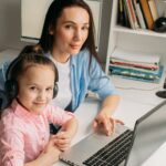 un enfant devant un écran avec un parent à côté, qui regarde les paramètres avec lui.