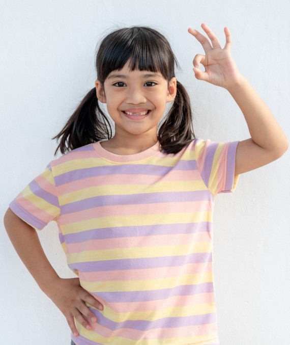 une jeune fille souriante avec un t-shirt rayé fait la signe OK