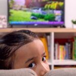 une jeune fille est assise devant la télé et se demande ce qu'elle regarde