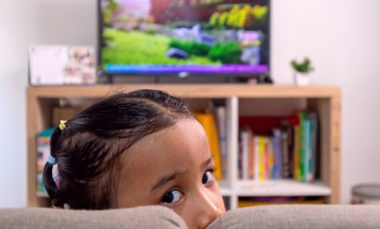 une jeune fille est assise devant la télé et se demande ce qu'elle regarde