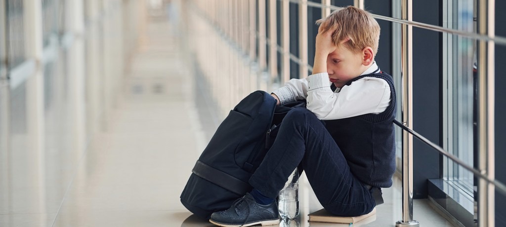 un garçon assis sur le sol, triste, se tient la tête