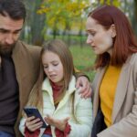 une famille assise sur un banc se demande comment limiter l'accès au smartphone