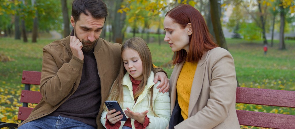 une famille assise sur un banc se demande comment limiter l'accès au smartphone