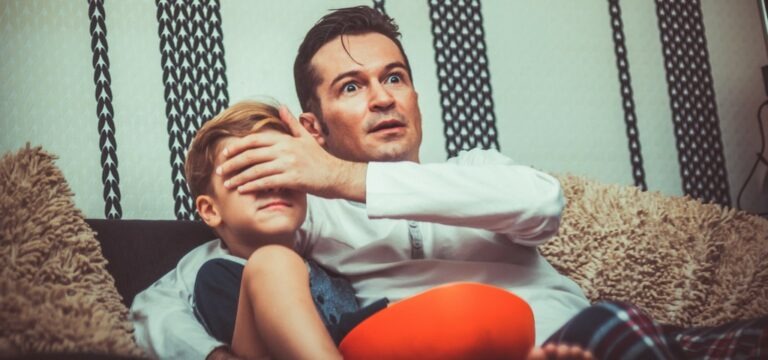 un père et son fils devant la télé, le pere cache les yeux de l'enfant pour qu'il ne vois pas le contenu horrifique