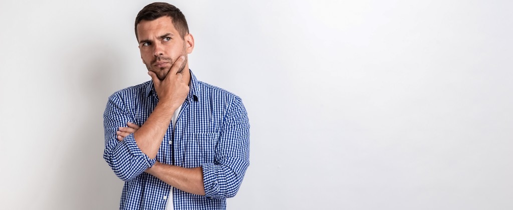 un homme en chemise, main au niveau de menton, en pleine réflexion