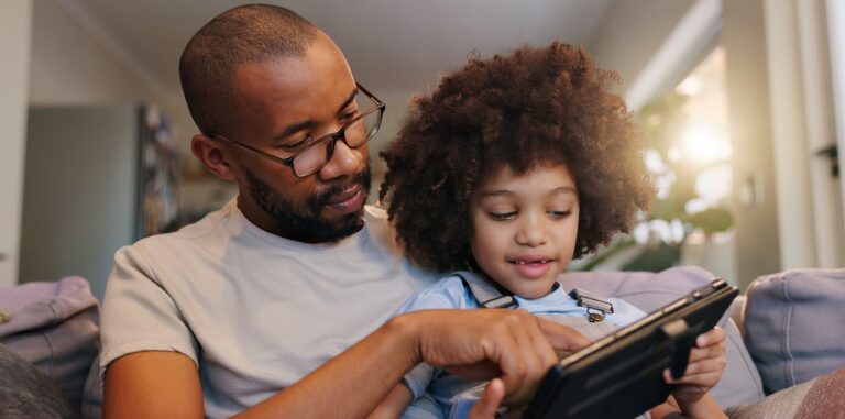 un père et son enfant, sérieux, devant la tablette