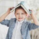 un enfant, sur de lui, utilise un livre comme un chapeau