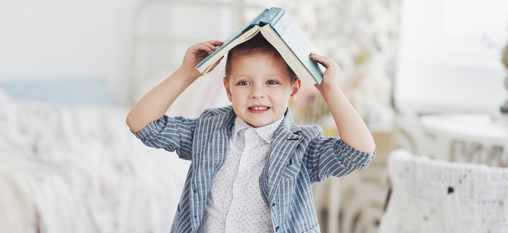 un enfant, sur de lui, utilise un livre comme un chapeau