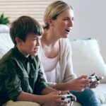 une mère et son fils jouent a un jeu vidéo dans le salon