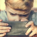 un enfant, l'air sérieux est concentré sur son smartphone