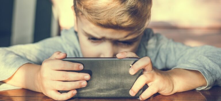 un enfant, l'air sérieux est concentré sur son smartphone