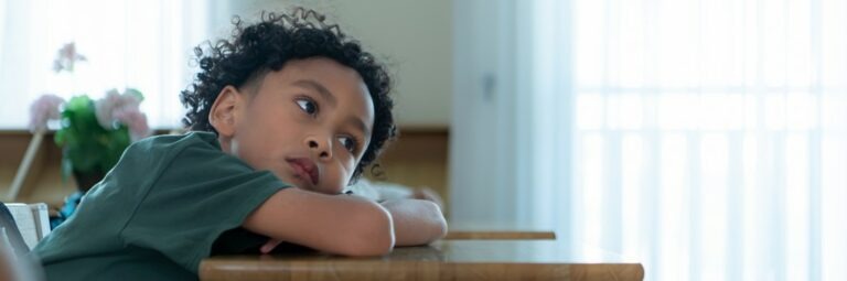 un enfant, la tête posée sur son bureau, il s'ennuie